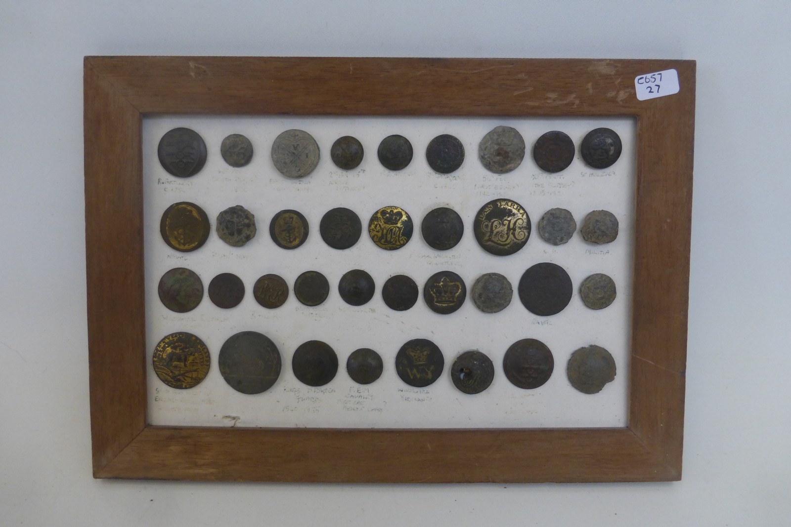 A framed display of metal detector finds of thirty-six military buttons.