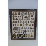 A framed display of 70 assorted military badges.