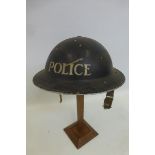 A WW2 Police helmet with liner and damaged chin strap.