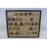 A framed display of 37 British military cap and lapel badges.