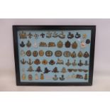 A framed display of 61 British military cap badges.