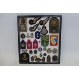 A framed display of thirty-two assorted badges.