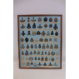 A framed display of 67 British military cap badges and shoulder titles.