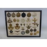 A framed display of 35 British military cap and lapel badges.