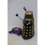 A Dr. Who Dalek in black and gold with a remote control 12 1/4 inches high.