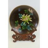 A Chinese cloisonne dish plate decorated with flowers and a bird, complete with carved wooden stand,