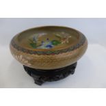 A Chinese cloisonne bowl decorated with flowers and birds, complete with carved wooden stand,