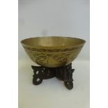 A Chinese brass bowl with engraved decoration and seal to the base, complete with carved wooden