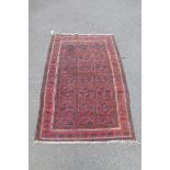 A Balouchi rug with repetitive medallions on a red ground, 40 x 61".