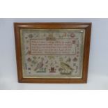 An early 19th Century maple framed sampler decorated with peacocks, birds, figures, houses etc, by