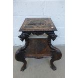 A Chinese two tiered lamp table with all over decoration, raised on four carved cloud dragon