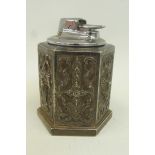 A Ronson table lighter set into a hexagonal shaped base with embossed decoration depicting religious