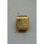 A gold (unmarked) gentleman's signet ring monogrammed and set with a light blue sapphire,