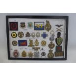 A framed display of 31 military, police and ambulance badges. All appear to retain their fixings