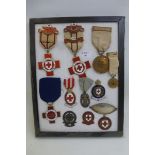 A framed display of mainly WWI British Red Cross Society medals, badges and an identity tag,