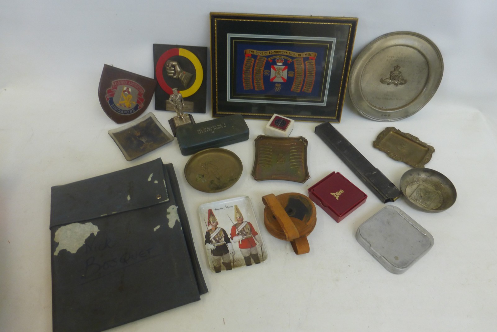 An assortment of military items including a map case, plaques, ashtrays, coasters etc.