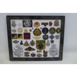 A framed display of 39 police and military badges. The Gloucestershire Constabulary helmet badge