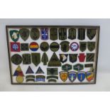 A framed display of 46 mainly U.S. military cloth badges.