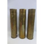 Three large WWI brass shell cases approximately 13 3/4" by 3 1/4" diameter.