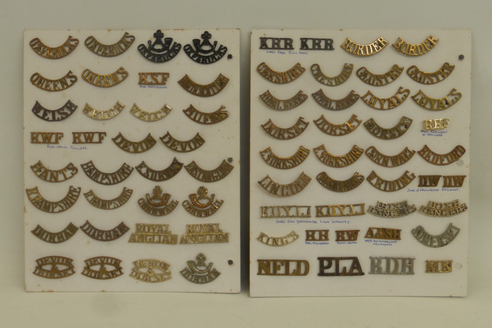 Two display cards of 70 brass and staybrite shoulder titles including Ox & Bucks, Queens, Royal