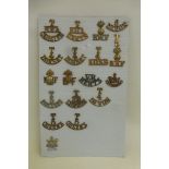 A display card of 18 brass and white metal shoulder titles, mainly Territorials including T. R.F.