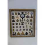 A framed display board of 51 police, fire brigade, Post Office and military badges and buttons.