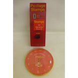 A plastic postage stamp dispenser and a Royal Mail circular wall clock.