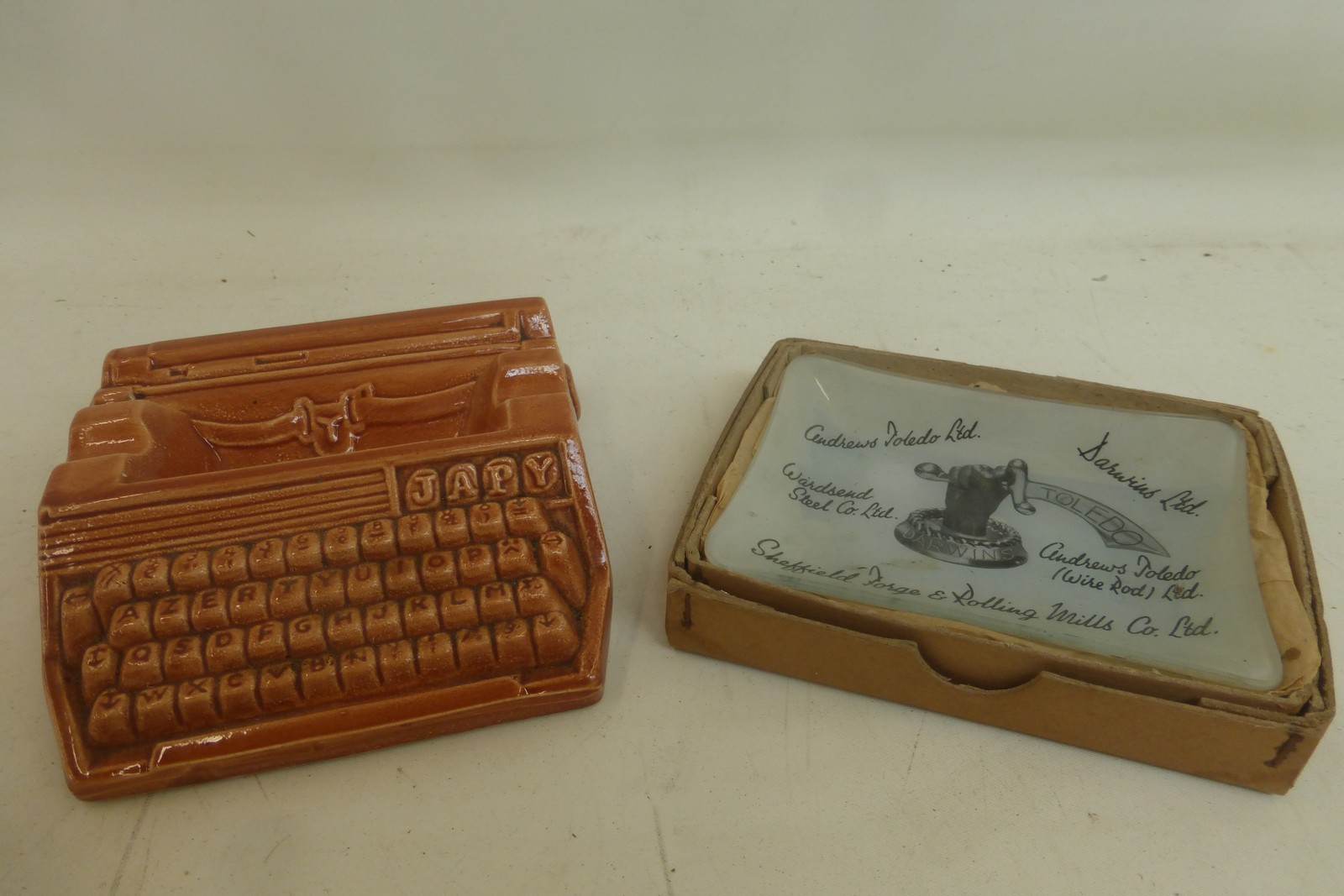 An unusual ceramic ashtray in the shape of a Parisian Japy typewriter and two others in glass for
