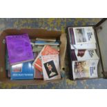 A box of assorted reference books and catalogues on coinage, postcards, symbols, etc. and a suitcase