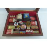 A table top display case containing a good assortment of small tins including Huntley & Palmers, Oxo