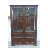 A contemporary oak lead glazed display bookcase with cupboard base, the door fronts with carved