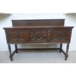 A 1930s/40s oak sideboard of three cupboards with geometric mouldings to the door fronts, raised