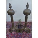 A large pair of brass fire dogs with reeded columns and flared finials.