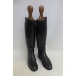 A pair of black leather riding boots with wooden boot trees.