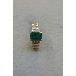 A 14k gold ring set with a large emerald and six rows of diamonds.