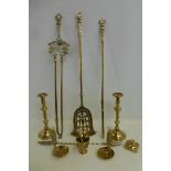 An ornate set of fire irons, a pair of brass candlesticks and various other brassware.