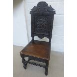 An 18th Century style oak hall chair carved with a coat of arms above a medieval battle scene on the