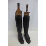 A pair of black leather riding boots with wooden boot trees.