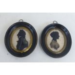 A pair of 19th Century oval silhouettes of a gentleman in military dress and a lady, both in side