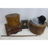 An Edwardian toleware oval hat box, a circular wooden hat box and two small travelling suitcases;