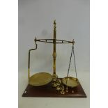 A good quality set of brass scales by Avery, set on a mahogany rectangular base, with five weights.