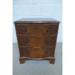 A reproduction walnut serpentine fronted chest of three drawers.