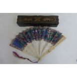 An Edwardian chinoisserie lacquered fan box containing an intricately carved and brightly