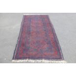 An Eastern woollen rug with six central medallions on a red ground, 48 x 90".