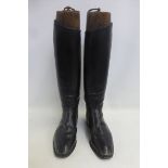 A tall pair of black leather gentleman's riding boots with wooden boot trees.