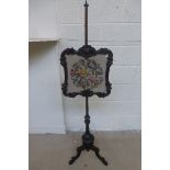 A Victorian carved rosewood pole sceen with needlework floral pattern, raised on a pierced tripod