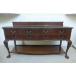 An Edwardian mahogany sideboard with raised upstand and carved frieze above four drawers and pot