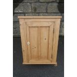 A pine single door wall hanging cupboard, with two small drawers inside.