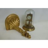 A gilded brass mantle clock set under a glass dome, set upon a gilded terracotta bracket.