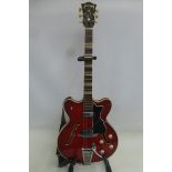 A cherry red Hofner Verithin Bigsby guitar in case.